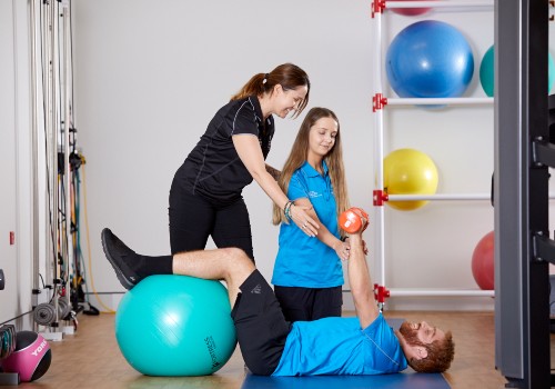 A patient of Exercise Physiology at UC Health Clinics using an exercise ball and free weights.