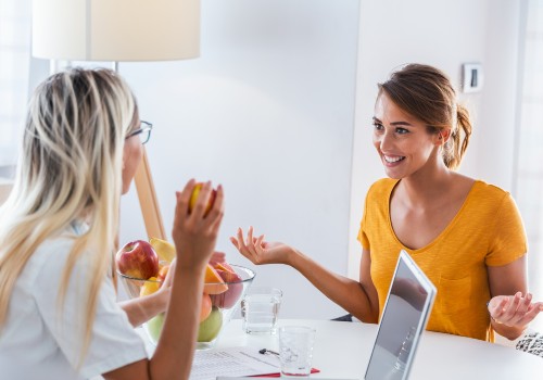 A woman giving advice on nutrition and dietetics to another woman over a white table, part of the services at UC Health Clinics.